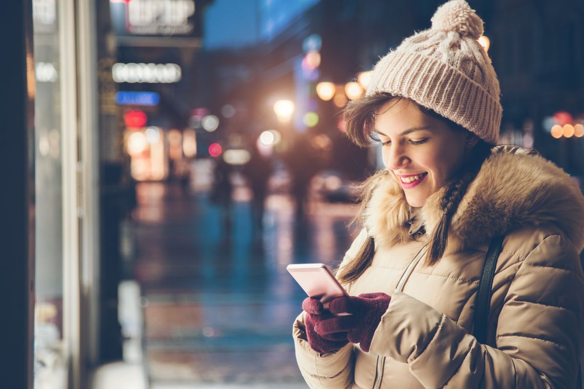 Frau hält Handy im Winter in der Hand