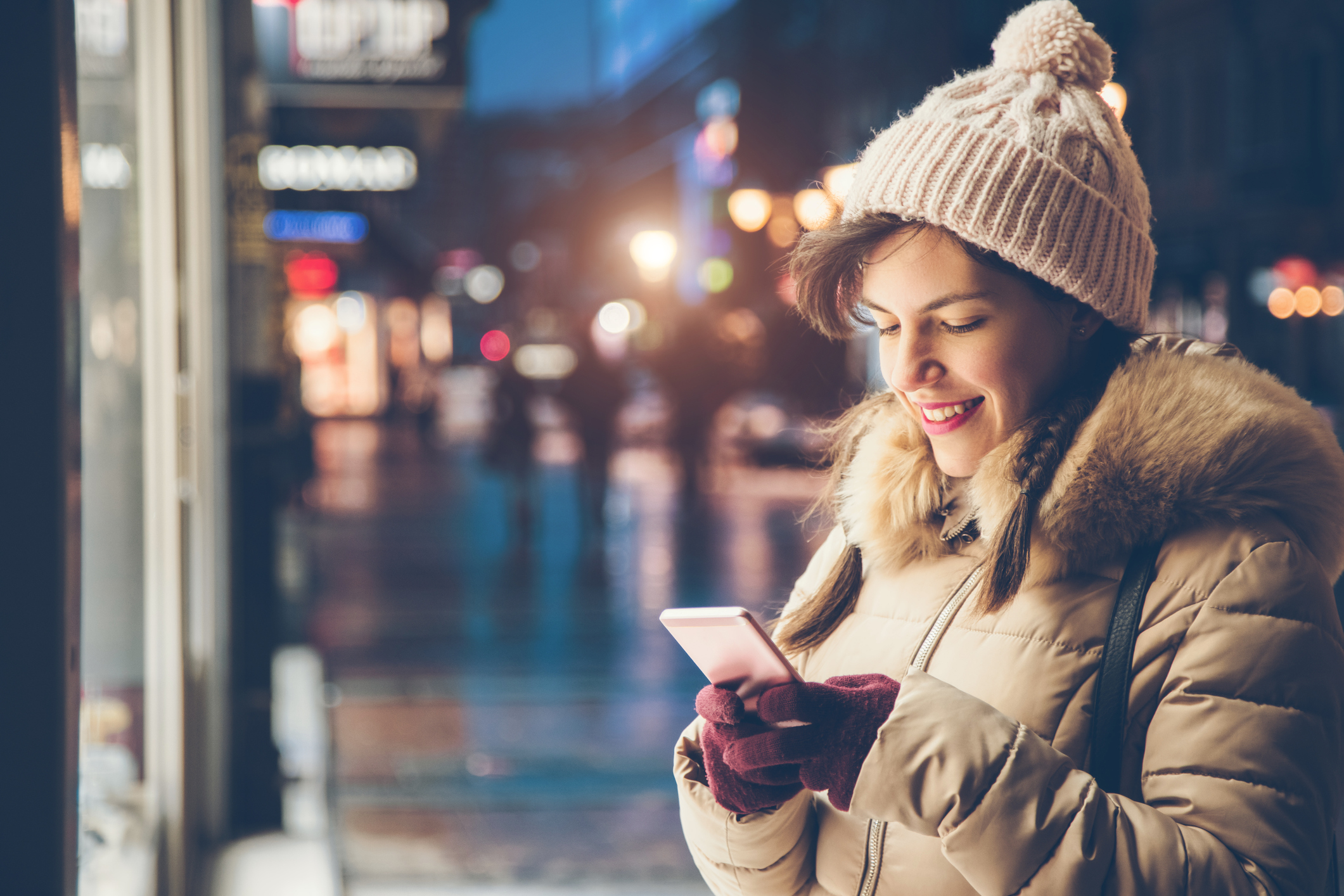 Frau hält Handy im Winter in der Hand